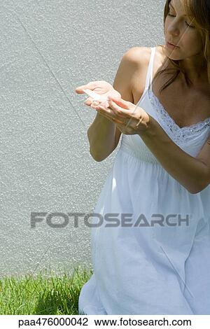 Stock Image - Woman in sundress holding butterfly in cupped hands. Fotosearch