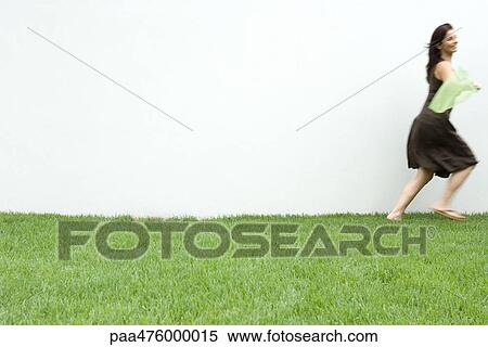 Stock Photography - Woman running in grass, side view. Fotosearch