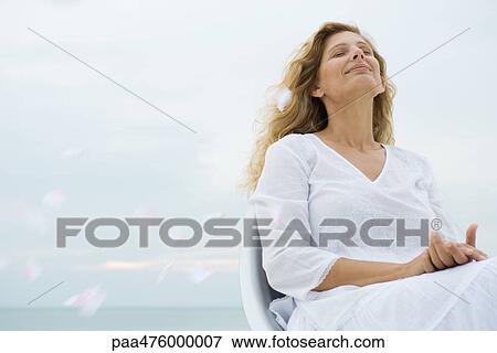 Woman sitting with head back and eyes closed among floating flower petals View Large Photo Image Stock Photo - Woman sitting with head back and eyes closed among floating flower petals. Fotosearch