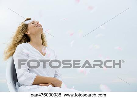 Woman sitting with head back and eyes closed among floating flower petals View Large Photo Image Stock Photo - Woman sitting with head back and eyes closed among floating flower petals. Fotosearch