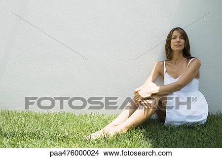 Woman wearing sundress sitting in grass and looking at camera View Large Photo Image Picture - Woman wearing sundress sitting in grass and looking at camera. Fotosearch