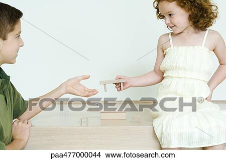 Picture - Boy and little sister playing with blocks, girl handing piece to brother. Fotosearch