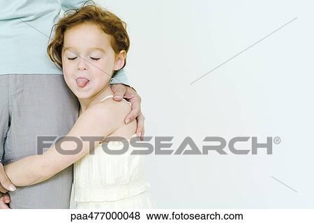 Little girl holding on to mother's leg, sticking tongue out at camera View Large Photo Image Stock Photo - Little girl holding on to mother's leg, sticking tongue out at camera. Fotosearch