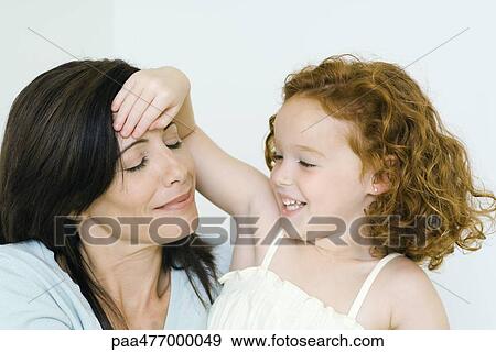 Stock Photo - Mother and daughter, girl's hand on woman's forehead. Fotosearch