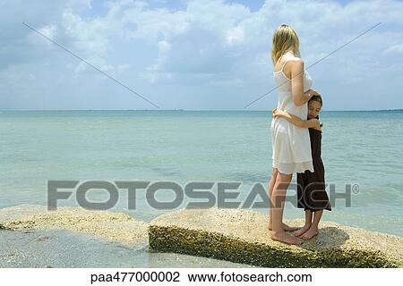 Mother and daughter standing by edge of sea, hugging, full length View Large Photo Image Stock Image - Mother and daughter standing by edge of sea, hugging, full length. Fotosearch
