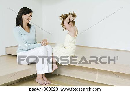 Mother and little girl, sitting together, smiling, girl holding up hair View Large Photo Image Stock Photo - Mother and little girl, sitting together, smiling, girl holding up hair. Fotosearch