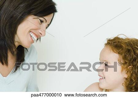 Stock Image - Mother smiling at little girl, cropped. Fotosearch