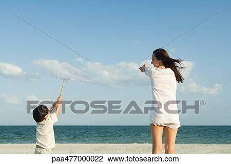 Stock Image - Woman and boy catching clouds, ocean horizon in distance. Fotosearch