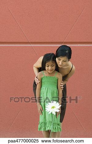 Woman and girl standing, looking at flower View Large Photo Image Stock Photography - Woman and girl standing, looking at flower. Fotosearch