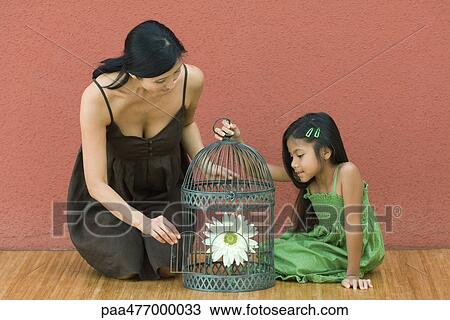 Woman and girl with birdcage containing flower, woman opening door View Large Photo Image Stock Image - Woman and girl with birdcage containing flower, woman opening door. Fotosearch