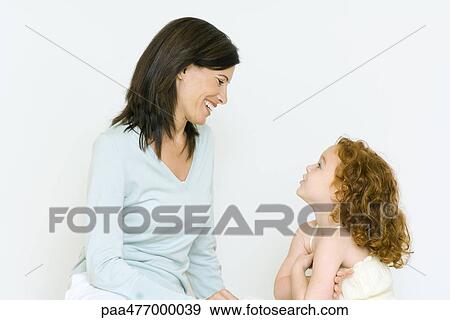Stock Photo - Woman and little girl having discussion, smiling. Fotosearch