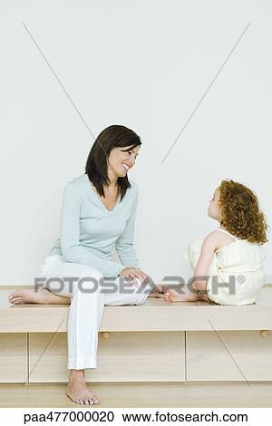 Woman and little girl sitting together, smiling at each other, full length View Large Photo Image Stock Image - Woman and little girl sitting together, smiling at each other, full length. Fotosearch