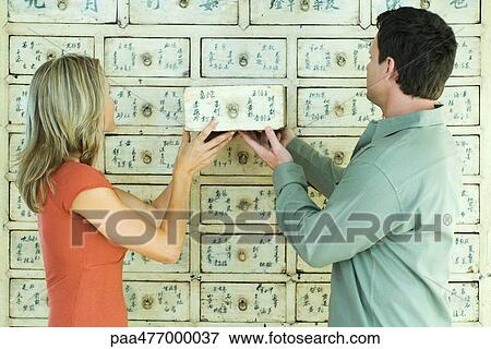 Stock Photo - Woman and man putting drawer into cabinet together. Fotosearch