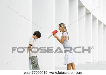 Stock Photo - Woman shouting at boy through megaphone, boy lowering head. Fotosearch