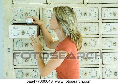 Stock Image - Woman taking glass ball from drawer. Fotosearch