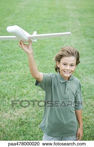 Boy holding up airplane, smiling at camera View Large Photo Image Stock Image - Boy holding up airplane, smiling at camera. Fotosearch