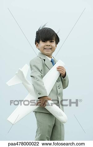 Little boy dressed in full suit, holding toy airplane, smiling at camera View Large Photo Image Stock Image - Little boy dressed in full suit, holding toy airplane, smiling at camera. Fotosearch