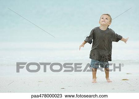 Little boy on beach, splashing, looking up View Large Photo Image Stock Image - Little boy on beach, splashing, looking up. Fotosearch