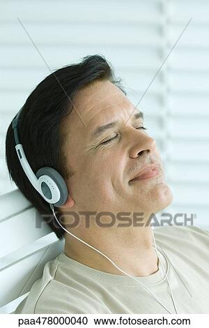 Man listening to headphones, smiling, eyes closed View Large Photo Image Stock Image - Man listening to headphones, smiling, eyes closed. Fotosearch