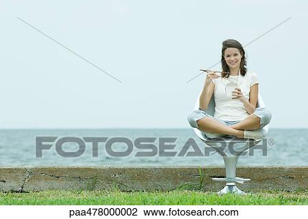 Teen girl sitting eating Chinese takeout food, ocean horizon in background View Large Photo Image Stock Image - Teen girl sitting eating Chinese takeout food, ocean horizon in background. Fotosearch