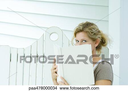 Woman looking over book at camera View Large Photo Image Picture - Woman looking over book at camera. Fotosearch