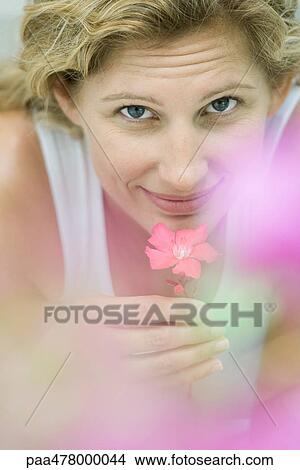 Woman smelling flower, looking at camera View Large Photo Image Picture - Woman smelling flower, looking at camera. Fotosearch