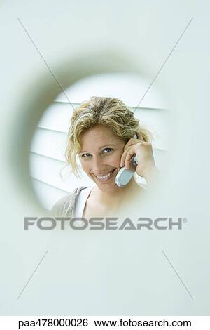 Woman using cell phone, framed by hole View Large Photo Image Stock Photograph - Woman using cell phone, framed by hole. Fotosearch