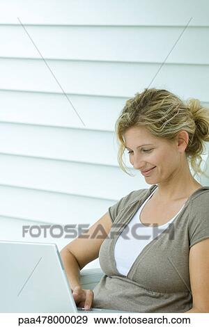 Woman using laptop, smiling, waist up View Large Photo Image Stock Photo - Woman using laptop, smiling, waist up. Fotosearch