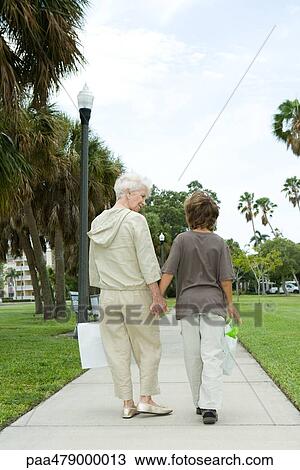 Boy and grandmother walking on sidewalk, carrying shopping bags, talking, rear view View Large Photo Image Stock Image - Boy and grandmother walking on sidewalk, carrying shopping bags, talking, rear view. Fotosearch