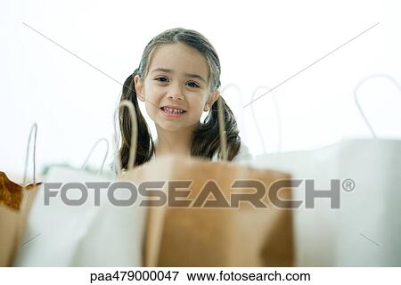 Stock Photo - Little girl smiling, shopping bags in foreground. Fotosearch