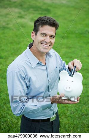 Man putting credit card into piggy bank View Large Photo Image Stock Photograph - Man putting credit card into piggy bank. Fotosearch