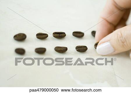 Stock Image - Woman placing coffee beans in lines. Fotosearch