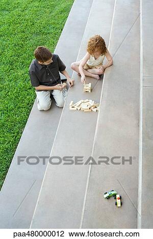 Stock Image - Brother and sister playing with blocks on stairs, high angle view. Fotosearch