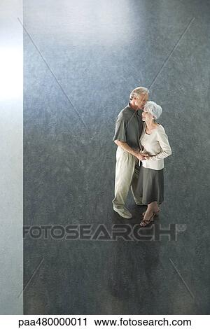 Couple standing together, holding hands, man whispering in woman's ear, high angle view View Large Photo Image Stock Image - Couple standing together, holding hands, man whispering in woman's ear, high angle view. Fotosearch