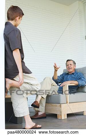 Grandfather and grandson chatting on patio together View Large Photo Image Picture - Grandfather and grandson chatting on patio together. Fotosearch