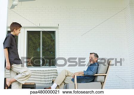 Grandfather and grandson together on patio, boy standing, man sitting View Large Photo Image Stock Image - Grandfather and grandson together on patio, boy standing, man sitting. Fotosearch