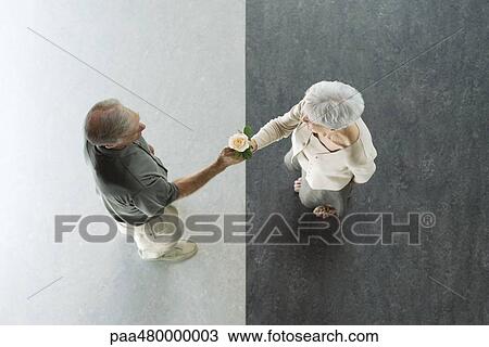 Stock Image - Senior man giving his wife a rose, viewed from directly above. Fotosearch