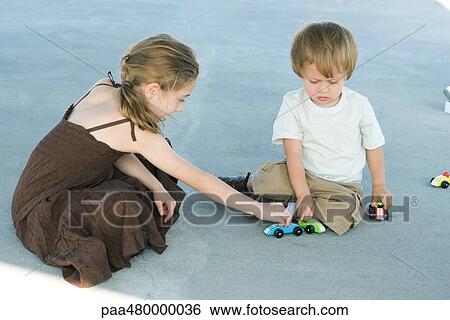 Sister and brother sitting on the ground playing with toy cars together View Large Photo Image Stock Photograph - Sister and brother sitting on the ground playing with toy cars together. Fotosearch