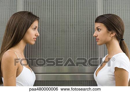 Teenage twin sisters face to face, looking at each other, side view View Large Photo Image Stock Photograph - Teenage twin sisters face to face, looking at each other, side view. Fotosearch