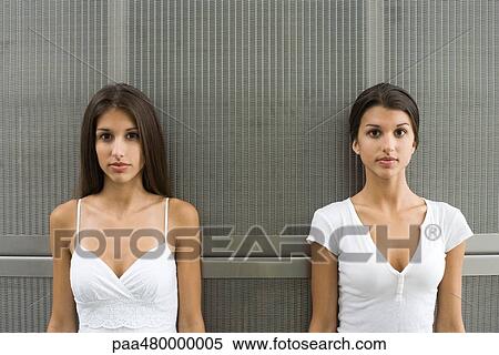Teenage twin sisters standing side by side, looking at camera View Large Photo Image Stock Photography - Teenage twin sisters standing side by side, looking at camera. Fotosearch