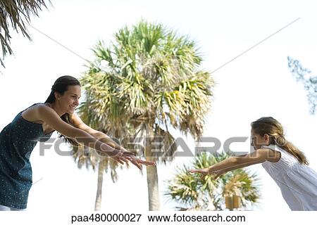 Two sisters reaching toward each other, arms outstretched, low angle view View Large Photo Image Stock Photo - Two sisters reaching toward each other, arms outstretched, low angle view. Fotosearch