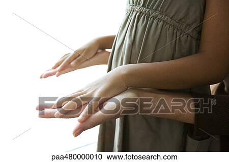 Stock Image - Woman holding girl's hands, cropped view. Fotosearch