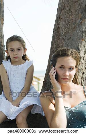 Young woman using cell phone, looking away, girl in background looking at camera View Large Photo Image Stock Photography - Young woman using cell phone, looking away, girl in background looking at camera. Fotosearch