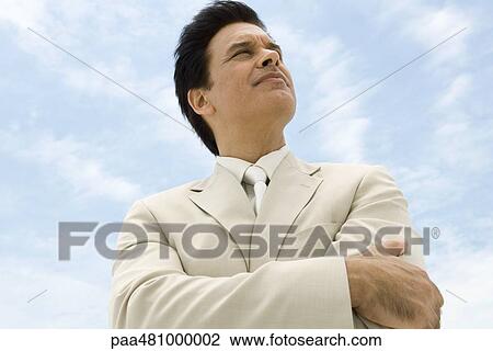Businessman with arms folded, looking up, smiling, low angle view View Large Photo Image Stock Image - Businessman with arms folded, looking up, smiling, low angle view. Fotosearch