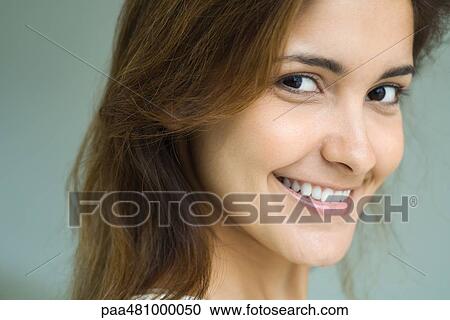 Stock Image - Female looking sideways at camera, smiling, portrait. Fotosearch