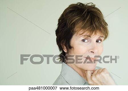 Stock Photo - Woman smiling at camera, hand under chin, portrait. Fotosearch