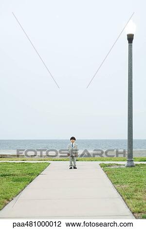 Young boy dressed in full suit, standing at end of path, looking at camera View Large Photo Image Stock Image - Young boy dressed in full suit, standing at end of path, looking at camera. Fotosearch