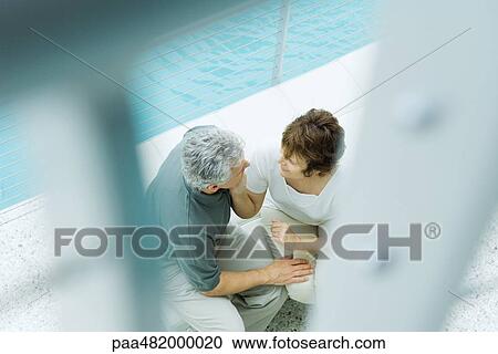 Couple sitting next to pool, high angle view, selective focus View Large Photo Image Stock Image - Couple sitting next to pool, high angle view, selective focus. Fotosearch