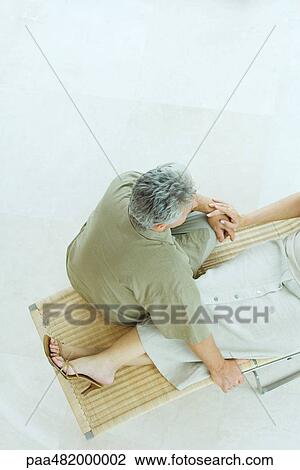 Couple sitting together on lounge chair, high angle view, cropped View Large Photo Image Stock Image - Couple sitting together on lounge chair, high angle view, cropped. Fotosearch