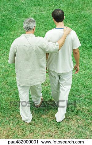 Stock Image - Father and adult son walking together outdoors, rear high angle view. Fotosearch